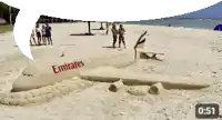 a sand sculpture of an emirates airplane is on the beach