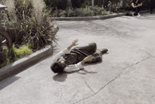 a man is laying on the ground while a woman sits on the sidewalk