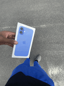 a person holding a blue iphone in its box