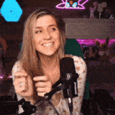 a woman is smiling while sitting in front of a microphone in a room .