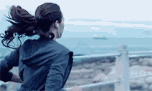 a woman wearing headphones is running on a beach near the ocean .