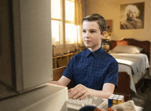 a young boy in a blue shirt is typing on a computer keyboard