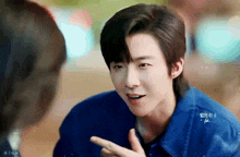 a young man in a blue jacket is talking to another man .