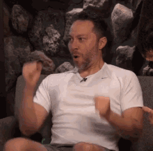 a man with a beard is sitting on a couch with his arms outstretched .
