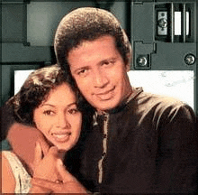 a man and a woman are posing for a picture . the woman is hugging the man .
