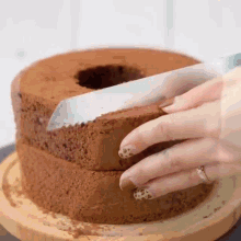 a woman is cutting a chocolate cake with a knife .