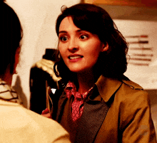 a woman in a trench coat is talking to another woman in a pink shirt