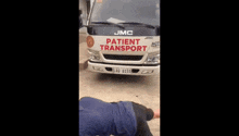 a man laying on the ground in front of a patient transport truck