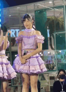 a girl in a purple dress is holding a microphone