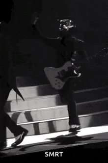 a black and white photo of a man playing a guitar on stage .