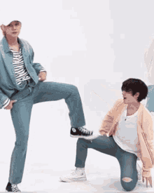 a man is kicking another man 's leg while kneeling down on the floor .