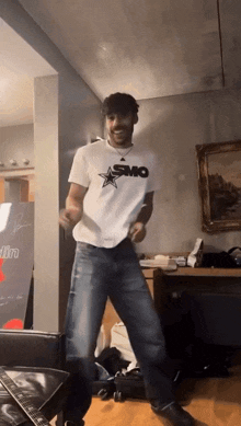 a man wearing a smo shirt is dancing in a room