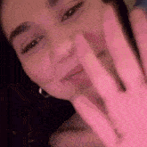 a close up of a woman 's face with a pink hand .