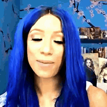 a woman with blue hair is smiling in front of a wall with pictures on it