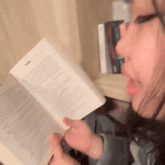 a woman is reading a book while sitting on a couch .