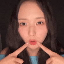 a woman making a funny face with her fingers in front of her mouth