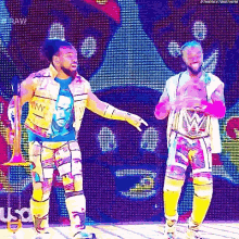two men are standing next to each other on a stage in front of a large screen .