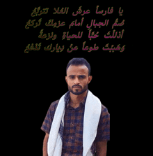a man with a scarf around his neck is standing in front of a black background with arabic writing