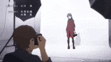 a man is taking a picture of a woman in a red coat in front of a white background