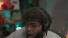 a man with a beard wearing headphones is sitting in front of a computer screen .
