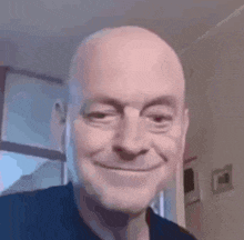 a bald man is smiling and looking at the camera while wearing headphones .