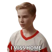 a boy wearing a red and white jersey says i miss home