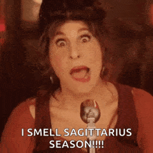 a woman is singing into a microphone and saying i smell sagittarius season