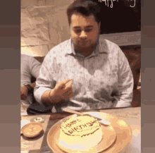 a man is sitting at a table with a cake that says happy birthday on it