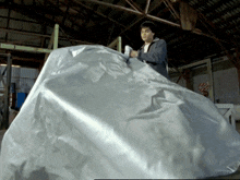 a man is standing in a warehouse holding a large silver object