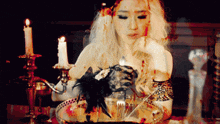 a woman is sitting at a table with candles and a bowl of food