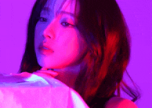 a close up of a woman 's face with red and purple lights behind her