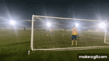 a soccer goalie stands in front of a soccer net with a bottle of water on the ground