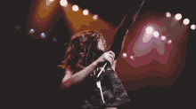 a woman is singing into a microphone while holding a guitar on a stage .
