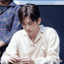 a young man in a plaid shirt looks down at something in his hand