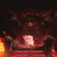 a cat with a pink bow sits on a throne