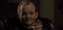 a man in a tuxedo and bow tie is holding a glass of whiskey