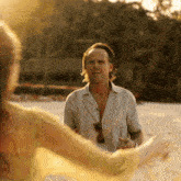 a man and a woman are dancing on the beach and the woman is wearing a yellow dress