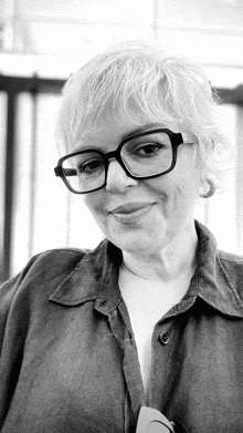 a black and white photo of a woman wearing glasses and a button up shirt