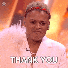 a man wearing a white jacket and feathers says thank you