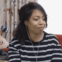 a woman wearing ear buds and a striped shirt looks down