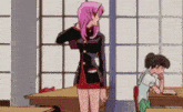 a girl with pink hair is standing in a room next to a girl sitting at a desk .