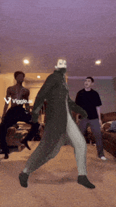 two men are dancing in a living room with a purple background and the words viggle.ai in the corner