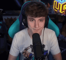 a young man wearing headphones is sitting in front of a microphone with a cube in the background