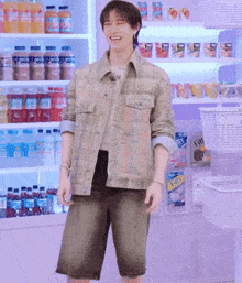 a man wearing a plaid jacket and shorts is standing in front of a fridge full of bottles of soda