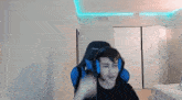 a young man wearing headphones and a microphone is sitting in a gaming chair .