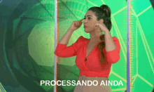 a woman in a red top is standing in front of a green background with the words processando ainda written on it