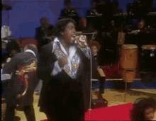 a man in a suit singing into a microphone on a stage