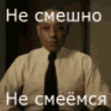 a man in a suit and tie is sitting at a table with a foreign language on the screen .