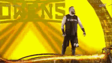 a man in a black tank top and shorts is standing in front of a yellow background .