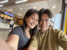 a man and a woman are posing for a picture in front of a mcdonald 's menu